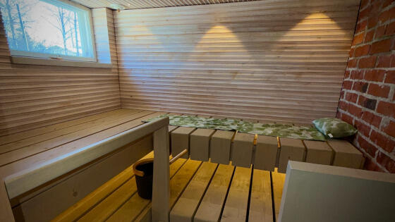 Moderni saunaremontti Uudellamaalla: uudet vaaleat lauteet ja tyylikäs panelointi viimeisteltynä valaistuksella.